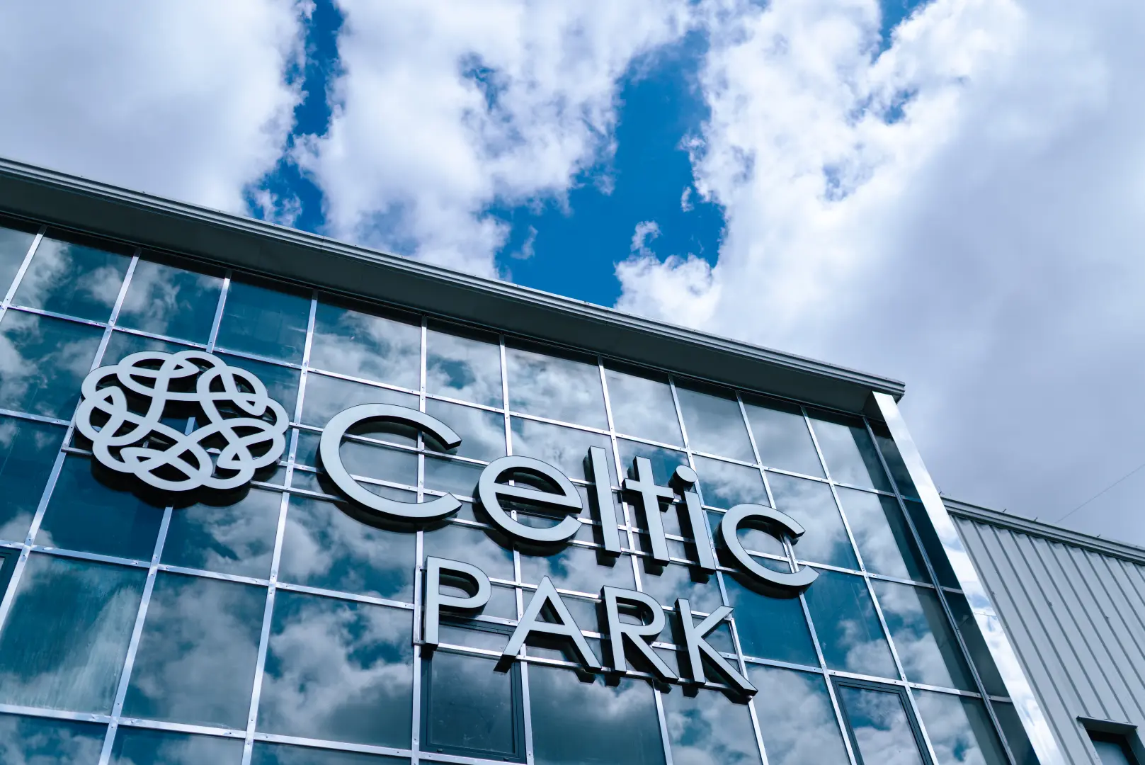 Logo Celtic Park na szklanej fasadzie budynku w Łomiankach — zbliżenie