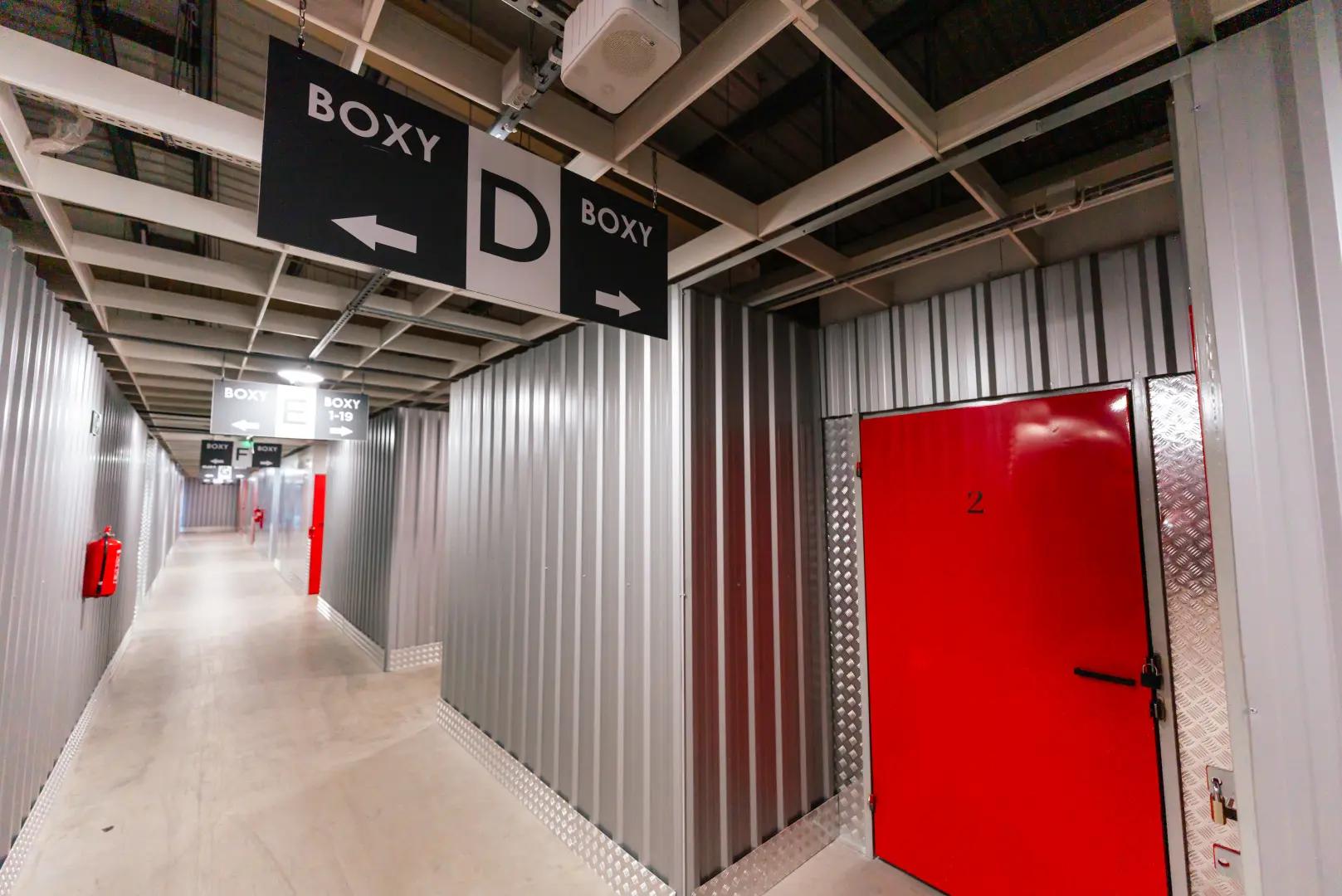 Korytarz magazynowy Celtic Self Storage Łomianki — oznakowanie BOXY D i czerwone drzwi
