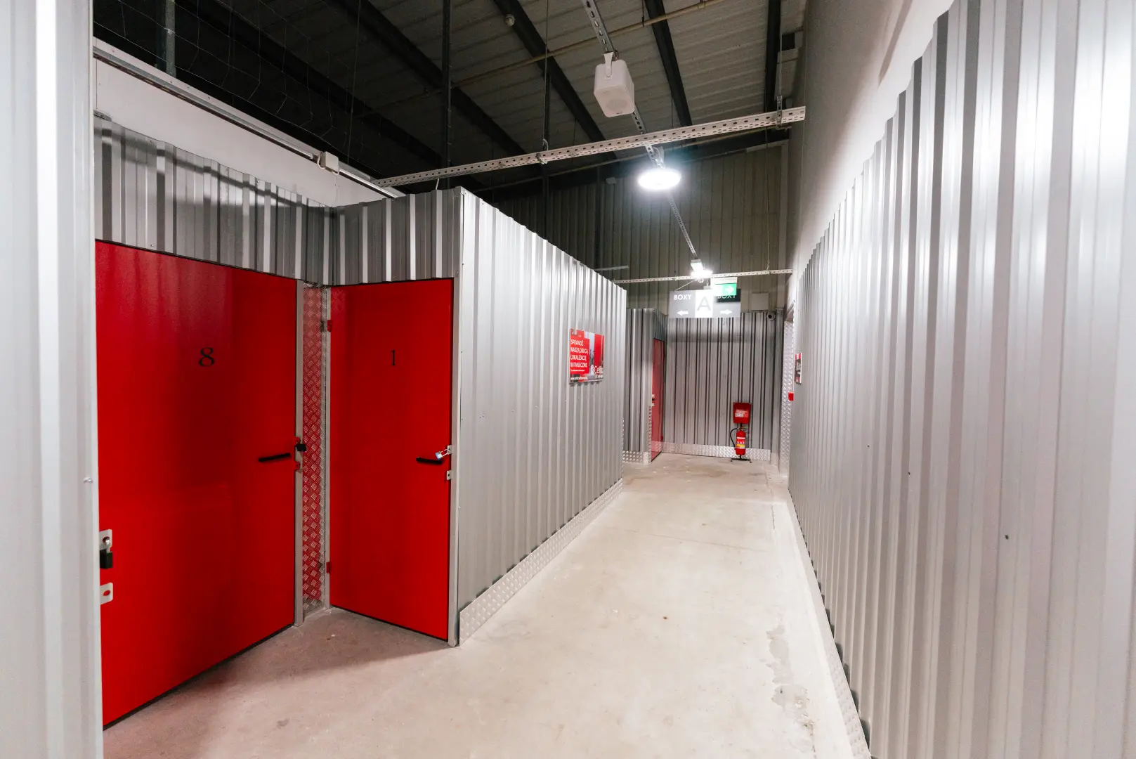 Korytarz z czerwonymi drzwiami boksów magazynowych w Celtic Self Storage Łomianki — boksy A