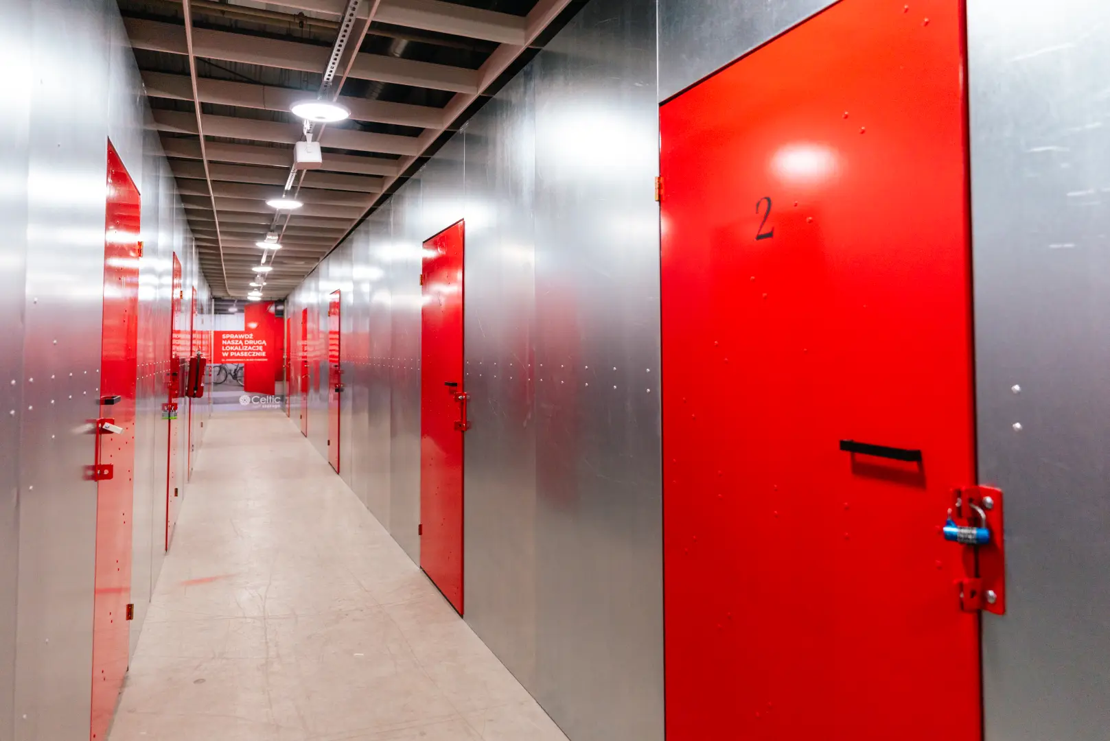 Długi korytarz z boksami i banerem Celtic Self Storage w Piasecznie